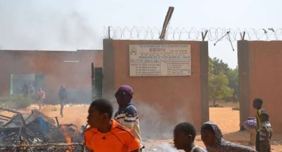 People stand in front of a church in Niger's capital Niamey on January 17, 2015 which was set on fire by protesters during a demonstration against French weekly Charlie Hebdo's publication of a cartoon of the Prophet Mohammed.  By Boureima Hama AFP