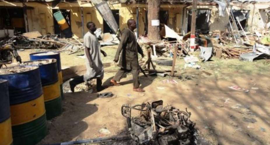 Two residents pass by bombed corner shops attached to Bompai police barracks in Kano in January.  By Aminu Abubakar AFPFile
