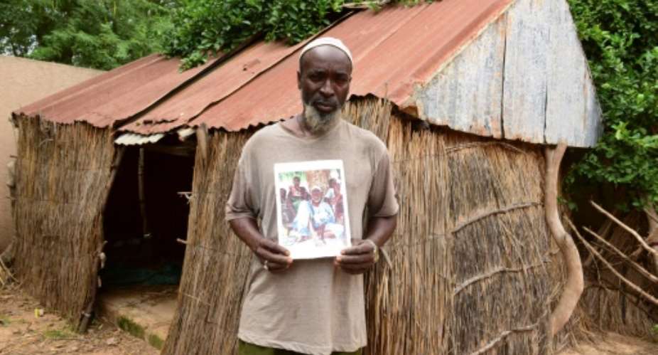Babacar Ndiaye poses with a photo of his grandfather Abdoulaye Ndiaye, a Senegalese villager who fought for France in World War I.  By SEYLLOU AFPFile