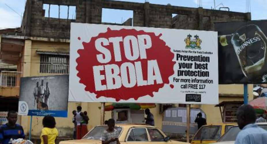 People walking past a billboard reading Stop Ebola in Freetown, Sierra Leone, November 7, 2014.  By Francisco Leong AFPFile