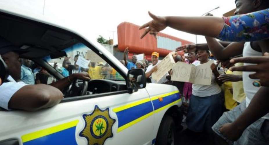 Protesters shout as a police car drives outside the Benoni court on March 8, 2013.  By Alexander Joe AFPFile