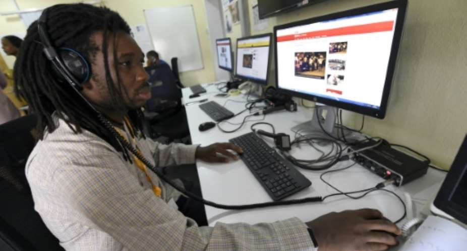 BBC programmer Busayo Iruemiode checks a website in Pidgin in Lagos, on August 18, 2017.  By AMELIE QUERFURTH AFP