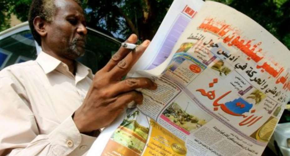 A Sudanese man reads a newspaper as he smokes a cigarette in the capital Khartoum.  By Ashraf Shazly AFP