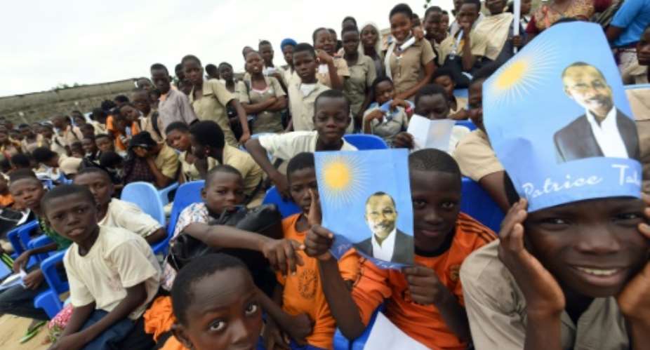 Pupils hold banners picturing presidential candidate and leader of the opposition coalition Patrice Talon during a rally in Ekpe, Benin on March 18, 2016.  By Pius Utomi Ekpei AFP