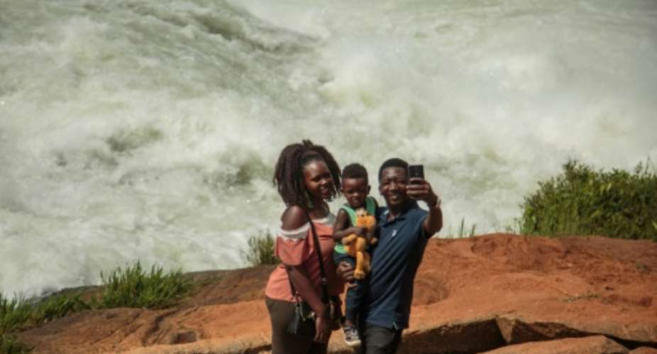 Big river: A family takes a selfie in front of the Nile during the Uganda National Kayaking Championships in Jinja in January. More than 250 people have died in selfie accidents around the world, according to a study published last year.  By Sumy SADURNI AFP