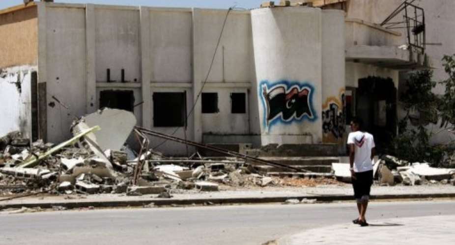 A young man walks past a destroyed militia building that was bombed by residents in Benghazi, Libya on April 29, 2013.  By Abdullah Doma (AFP/File)