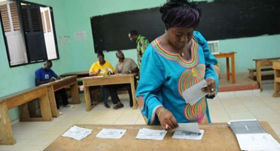 A woman takes ballot papers at a polling station during the legislative elections.  By Wils Yanick Maniengui AFPFile