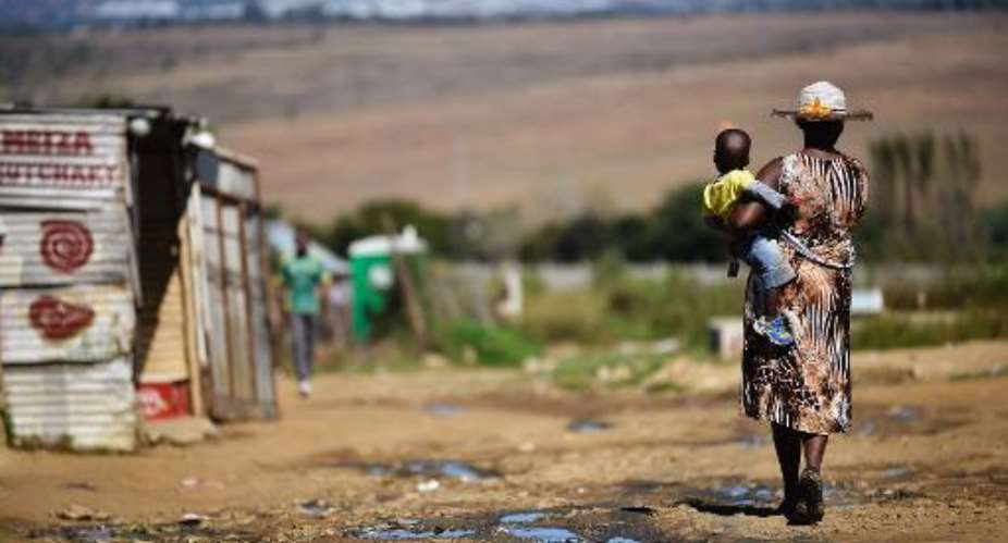 A woman carries her child as she walks in the impoverished township of Diepsloot on the outskirts of Centurion on April 24, 2014.  By Mujjahid Safodien AFP