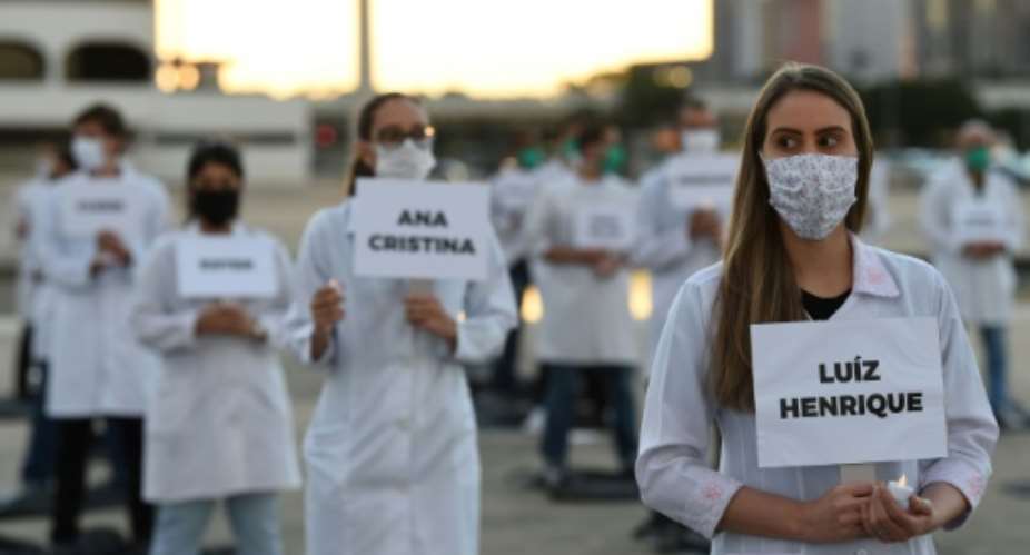 Brazilian nurses honor health workers who have died of COVID-19 during a demonstration in Brasilia.  By EVARISTO SA AFP