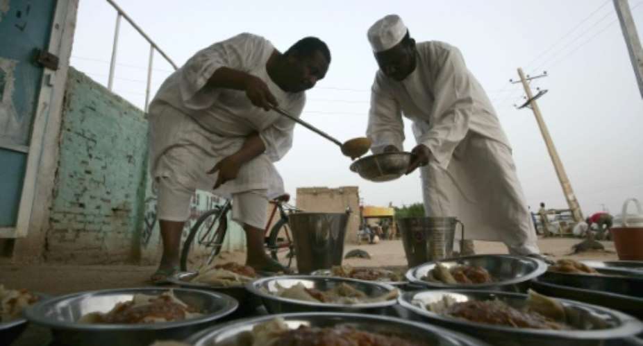 Sudanese men prepare food before an Iftar dinner by the side of the Khartoum highway in the village of al-Nuba Ramadan.  By Ebrahim Hamid AFP
