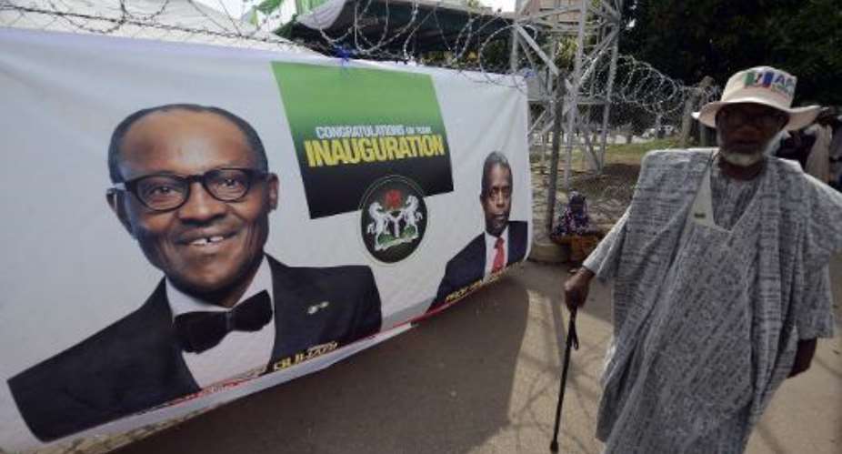 A man walks past a banner with portraits of Nigerian President-elect Mohammadu Buhari and Vice President Yemi Osinbajo at Eagle Square in Abuja on May 28, 2015 ahead of Friday's handover ceremony.  By Pius Utomi Ekpei AFP