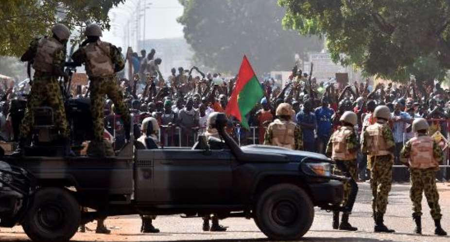 Troops face protestors who stormed parliament before setting it on fire in protest at plans to change the constitution on October 30, 2014 in Ouagadougou, Burkina Faso.  By Issouf Sanogo AFP