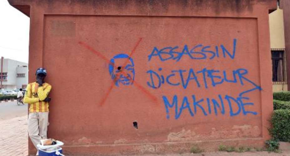A man stands near graffiti of ousted Burkinabese president Blaise Compaore that reads ''assassin, dictator, Makinde'', on the sidelines of negotiations on the transitional government on November 12, 2014 in Ouagadougou.  By Issouf Sanogo AFP