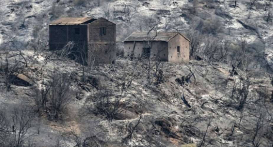 Burned houses stand amidst charred trees, on what used to be a forested hillside in Algeria's Kabylie region.  By Ryad KRAMDI AFP