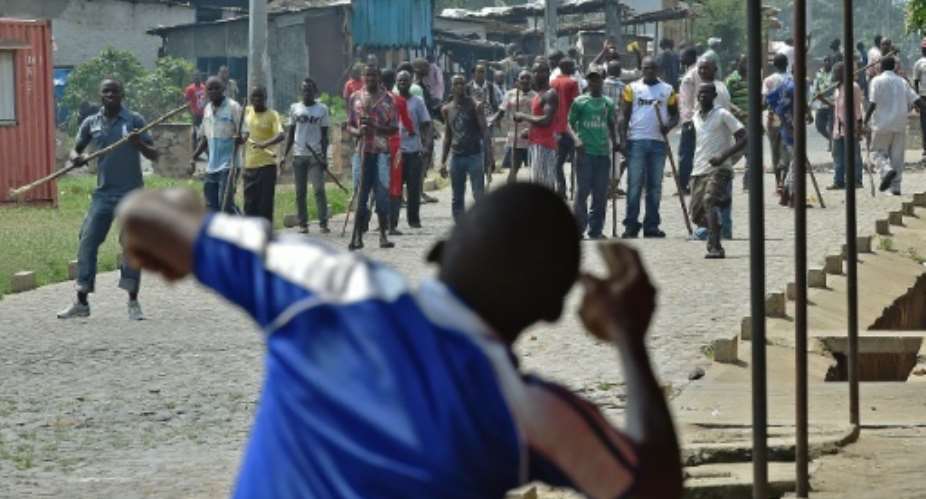 A protestor opposed to the Burundian President's third term throws a rock at members of the Imbonerakure, the youth wing of the ruling party, armed with sticks in the Kinama neighborhood of Bujumbura on May 25, 2015.  By Carl de Souza AFPFile