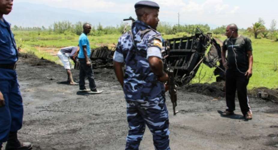 Burundi's police officers stand near the burnt truck after an attack on September 15th allegedly by a rebel from the neighboring Democratic Republic of Congo DRC at the border with DRC in Gatumba, western Burundi.  By Stringer AFP