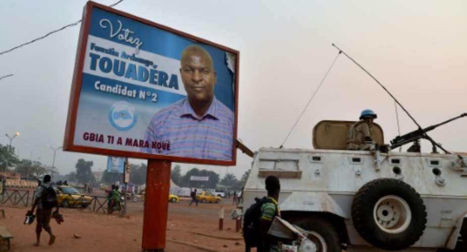 A UN peacekeeper sits on an armoured vehicle beside a campaign poster of Central African Republic second round presidential candidate Faustin Archange Touadera in Bangui on February 10, 2016.  By Issouf Sanogo AFP