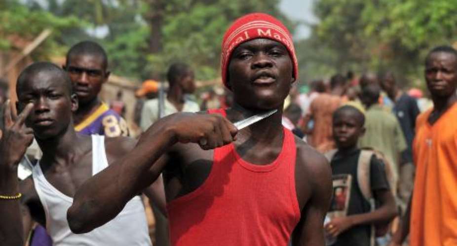 A man holds a knife to his throat claiming he is looking for Muslims to cut off their heads, in Bangui on February 9, 2014.  By Issouf Sanogo (AFP/File)