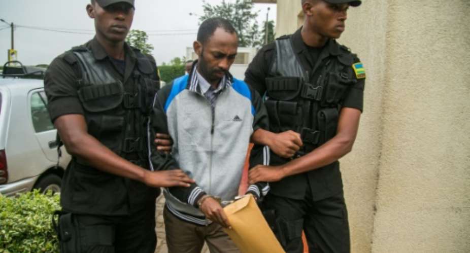 Callixte Nsabimana, spokesman for the National Liberation Front FLN, was escorted by police officers into the court in Kigali.  By Cyril NDEGEYA AFP