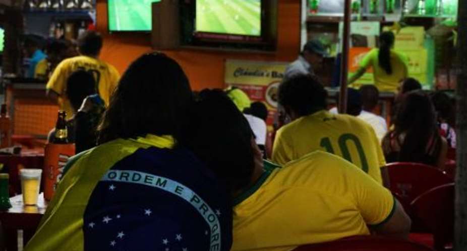 People watch the Brazil v Cameroon match on a television in Porto Seguro, on June 23, 2014, during the 2014 FIFA World Cup.  By Patrik Stollarz AFP
