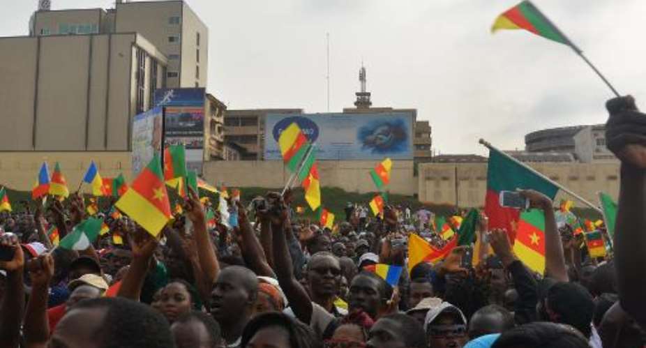 People wave Cameroon's national flag as they take part in a demonstration on February 28, 2015, in downtown Yaounde, against Islamist group Boko Haram.  By Reinnier Kaze AFP