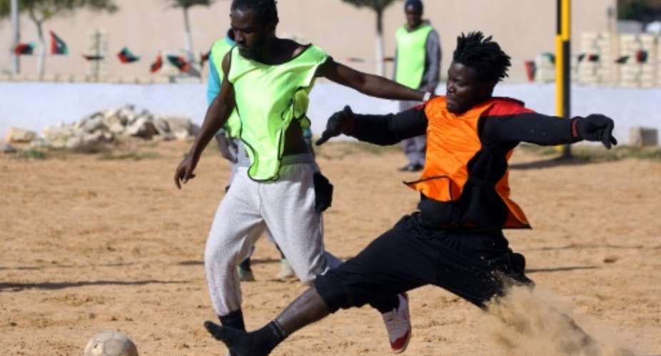 Cameroonian orange and Senegalese yellow migrants play football at the Libyan Interior Ministry's illegal immigration shelter in Tajoura, Tripoli, on February 28, 2018.  By MAHMUD TURKIA AFP