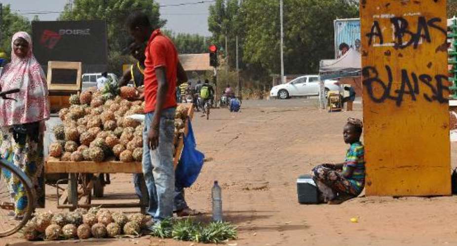 A vendor sells fruit next to graffiti reading Blaise out in Ouagadougou on November 20, 2014.  By Sia Kambou AFP