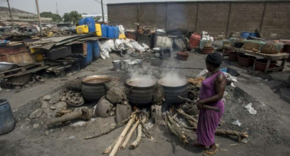 Cauldrons of the traditional sorghum-based pito drink bubble away in fire pits in Tema, Accra.  By CRISTINA ALDEHUELA (AFP)