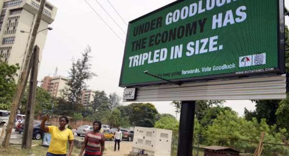 Two women walk past a campaign billboard of Nigeria's President Goodluck Jonathan and candidate for his re-election for the ruling People Democratic Party PDP, in the Ikoyi district of Lagos, on February 24, 2015.  By Pius Utomi Ekpei AFPFile