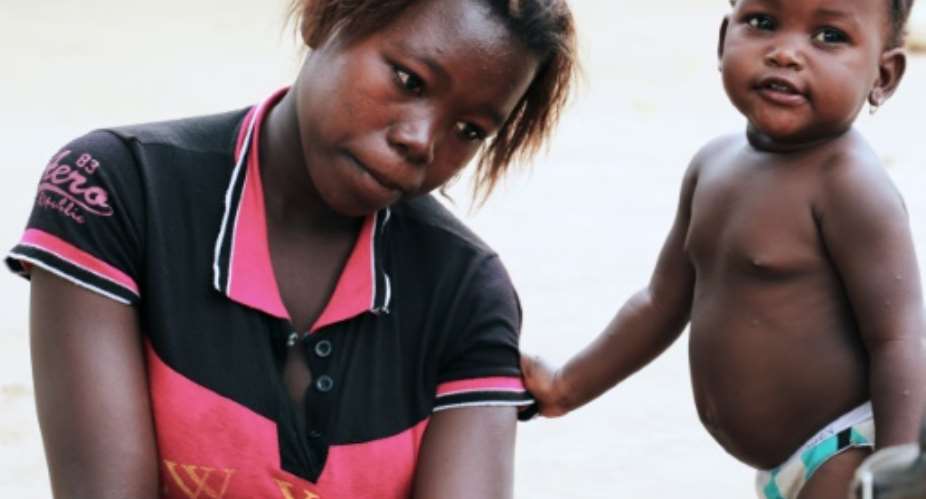 Albertina Ricardo, 17, sits next to her child in Inhambane, Mozambique.  By Adrien Barbier AFP