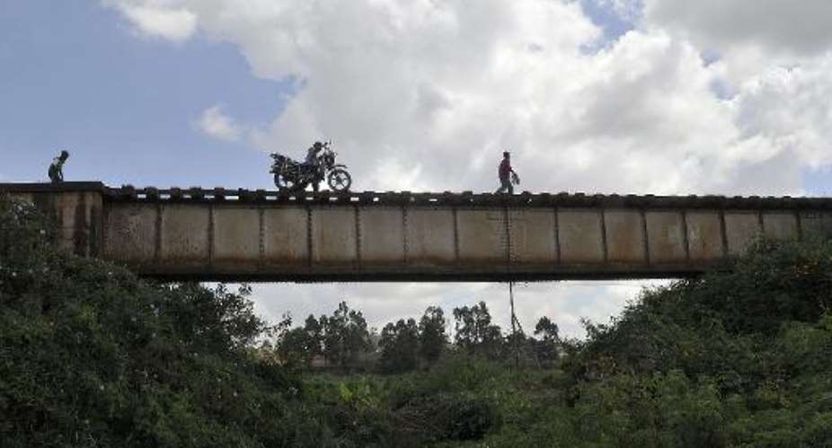 A man pushes his motorbike across a railway line bridge on November 7, 2014 in Nairobi.  By Simon Maina AFPFile