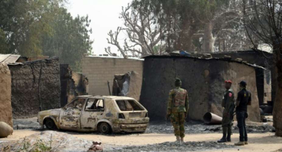 Nigerian soldiers inspect a burnt vehicle at the site of a suicide attack by the Boko Haram militant group in Maiduguri, northeast Nigeria on January 30, 2016.  By  AFPFile