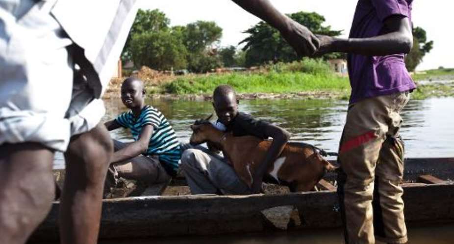 A young boy holds a goat as he prepares to cross the Nam river on a canoe into Tong in Bentiu, South Sudan, on March 23, 2014.  By Ivan Lieman AFPFile