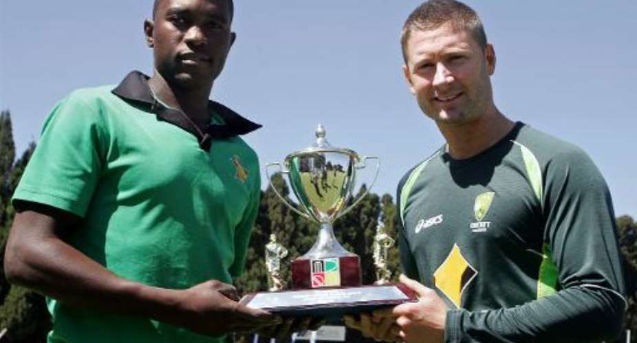 Zimbabwe captain Elton Chigumbura L holds the triangular series trophy with Australian counterpart Michael Clarke ahead of the tri-series including South Africa at the Harare Sports Club on August 24, 2014.  By Jekesai Njikizana AFPFile