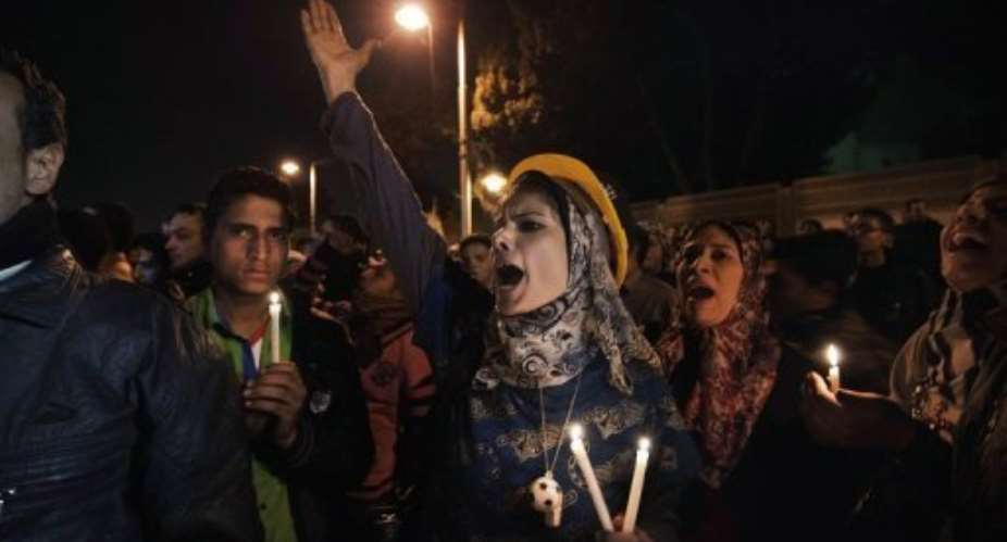 Protesters hold candles and shout slogans outside the Presidential Palace in Cairo on February 2, 2013.  By Gianluigi Guercia AFP