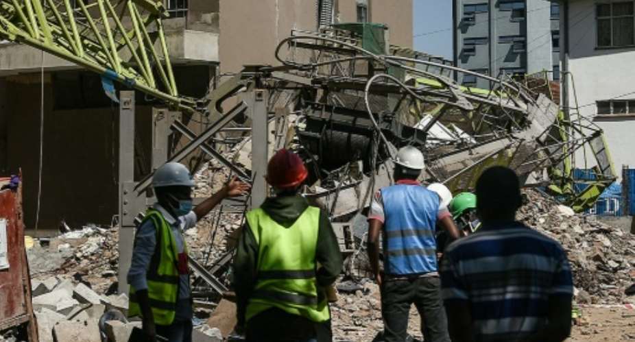 Contractors stand next to the collapsed crane in Kenya's capital Nairobi, on August 26, 2021..  By Simon MAINA AFP