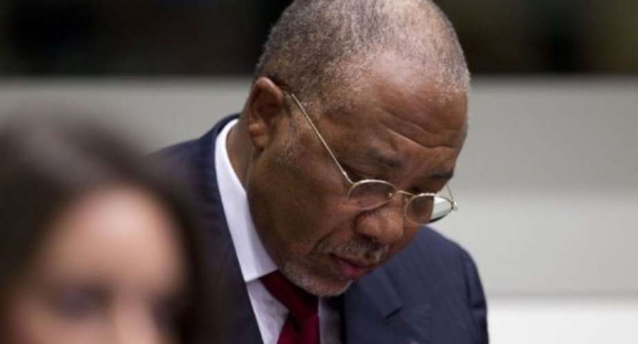 Former Liberian President Charles Taylor takes notes at the start of the judgement hearing of his trial in April.  By Peter Dejong (AFP/POOL/File)
