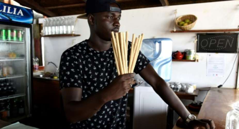 Copacabana restaurant owner Babacar Thiaw holds bamboo straws, replacing plastic straws -- a major and lasting source of marine pollution.  By SEYLLOU AFP