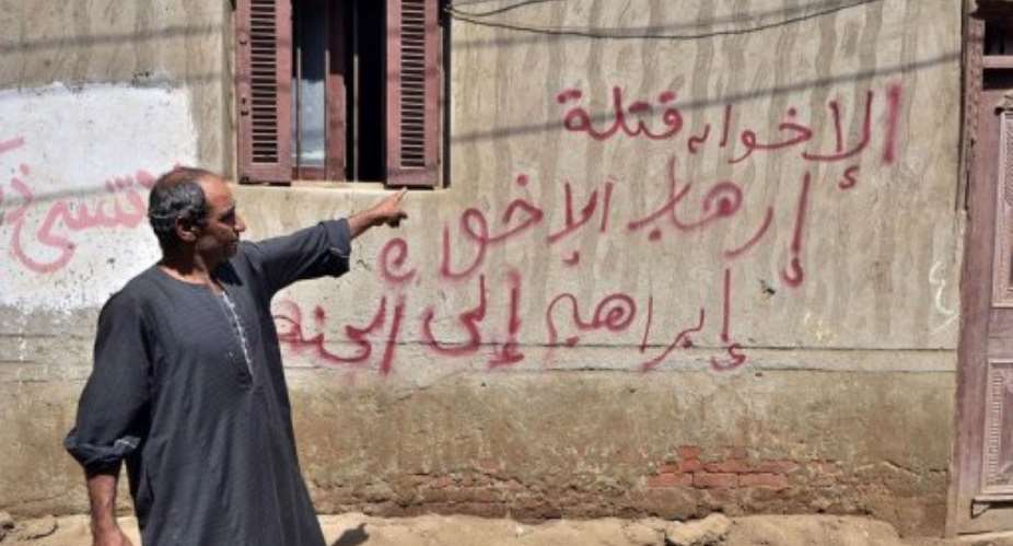A relative of a policeman killed in an attack in northern Sinai points to graffiti in Kafr el-Sawalmiya, August 20, 2013.  By Mohamed el-Shahed AFPFile