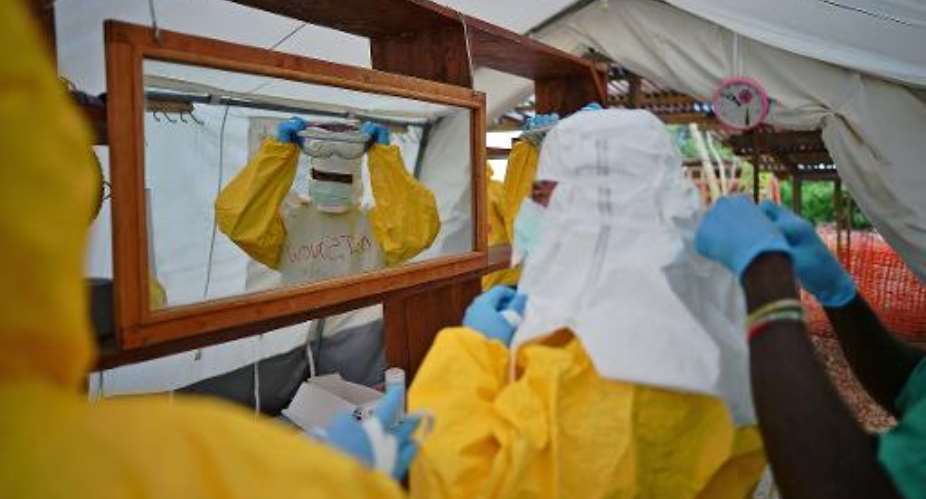 Health workers put on protective clothing at an MSF Ebola treatment facility in Kailahun, on August 15, 2014.  By Carl de Souza AFPFile