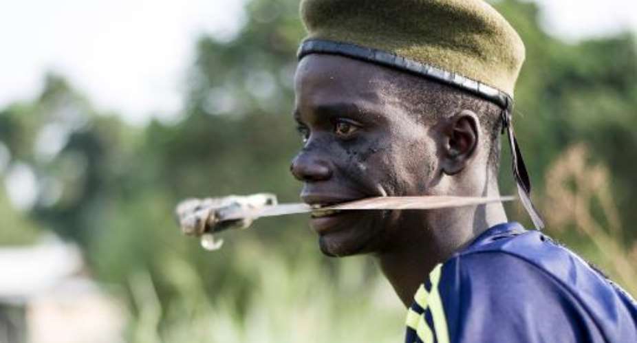 A file photo taken on February 24, 2014 shows a member of the mainly Christian anti-balaka anti-machete militia holding a blade in his mouth as he trains in the Boeing neighbourhood of Bangui, Central African Republic.  By Fred Dufour AFPFile