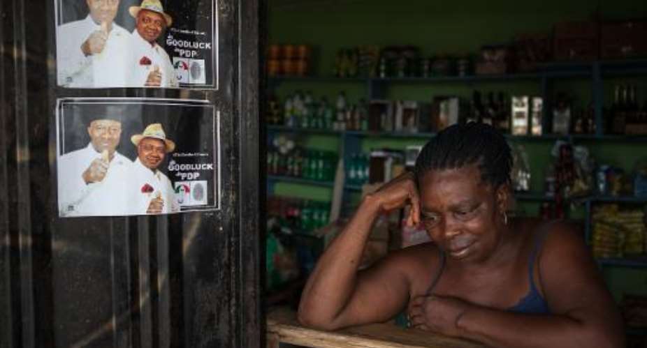 A woman on April 1, 2015 in her shop next to campaign posters of former Nigerian President Goodluck Jonathan, in Otuoke.  By Florian Plaucheur AFP