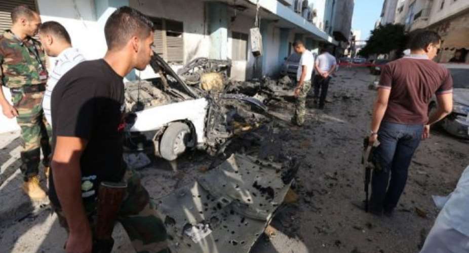 Libyan security forces inspect a bombed out vehicle near the Ministry of Interior.  By Mahmud Turkia (AFP)