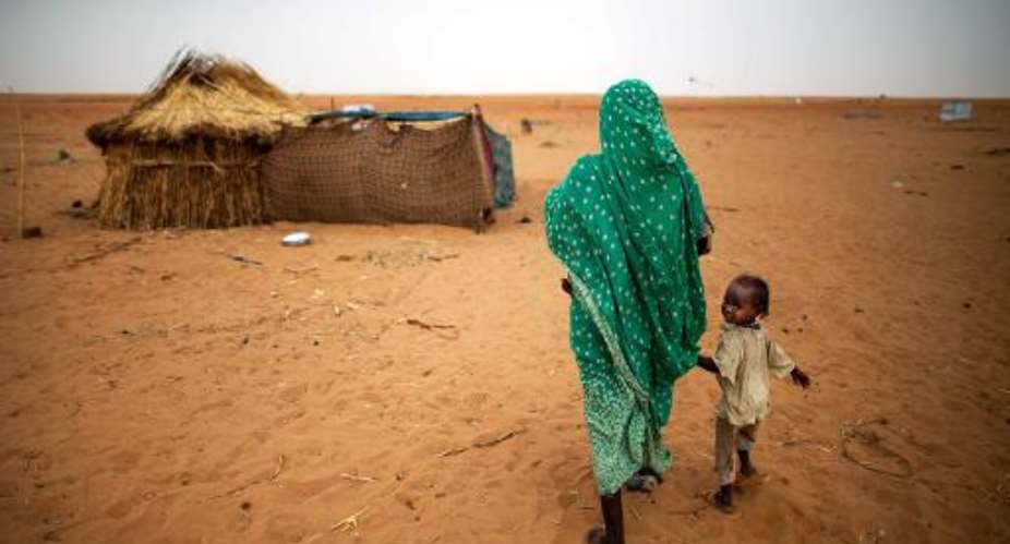 A child walking with her mother to their shelter in a new settlement in Zam Zam camp, North Darfur on June 11, 2014.  By Albert Gonzalez Farran UNAMIDAFP