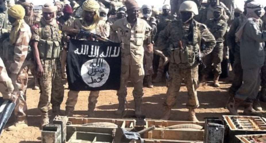 Chadian soldiers display an AQIM flag and weapons recovered after clashes with Islamists in northern Mali, March 3, 2013.  By Ali Kaya AFPFile