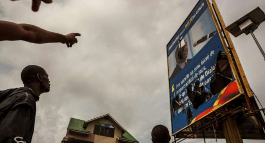 Demonstrators point a broken billboard showing the face of Congolese President Joseph Desiree Kabila during an opposition rally in Kinshasa.  By Eduardo Soteras AFPFile