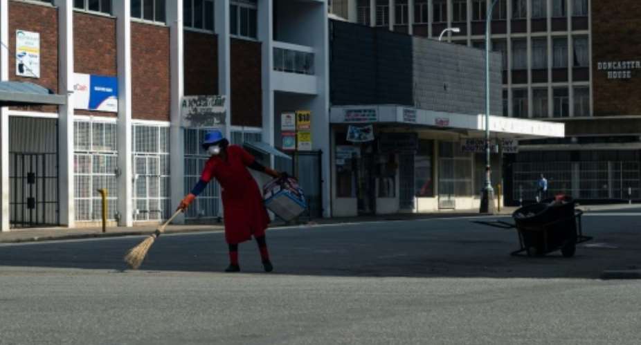 Deserted: A street cleaner in Harare on day one of Zimbabwe's three-week lockdown.  By Jekesai NJIKIZANA AFP