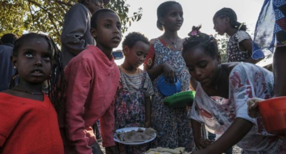 Displaced children receive plates of food outside a classroom in the school where they are sheltering in Tigray's capital Mekele in February 2021.  By EDUARDO SOTERAS AFPFile