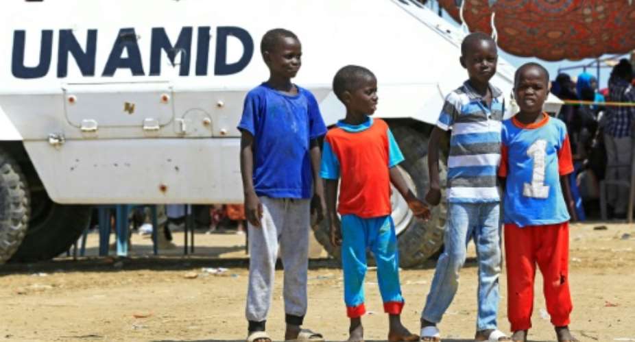 Displaced Sudanese boys pose for a picture in front of a UN-African Union mission to Darfur UNAMID vehicle at the Kalma camp for internally displaced people in Darfur's state capital Niyala on October 9, 2019.  By ASHRAF SHAZLY AFPFile