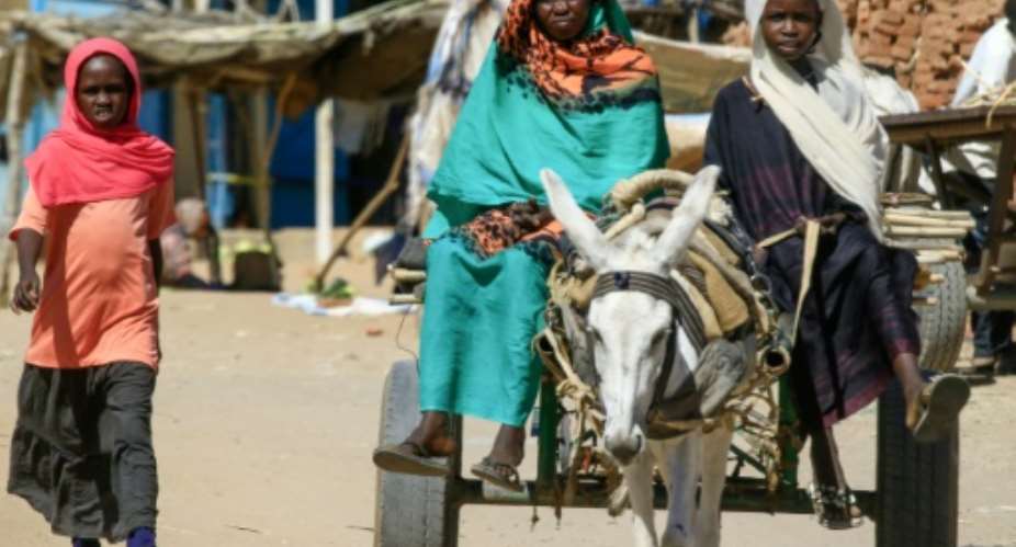Displaced Sudanese women ride on a donkey cart to move around the Abu Shouk camp, north of El-Fasher, the capital of North Darfur state.  By ASHRAF SHAZLY AFP